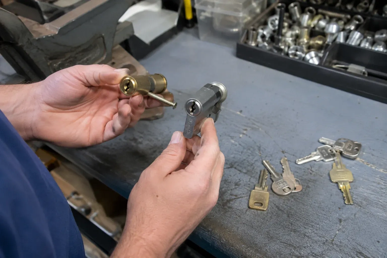 Hands comparing detached lock cylinders beside loose keys on a workbench. — Broken Key Extraction, King